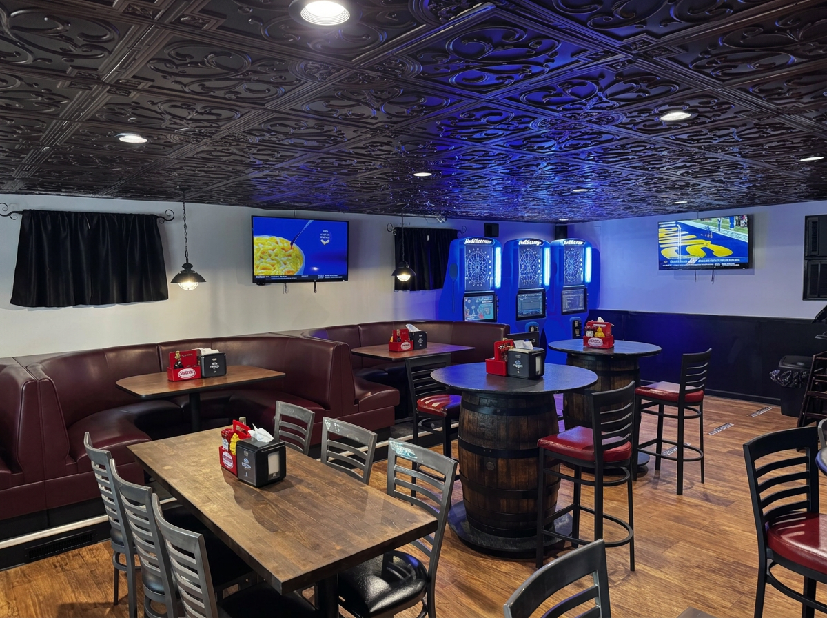 Inside The Shore House — maroon booths, barrel tables and dart machines under a dark tin ceiling